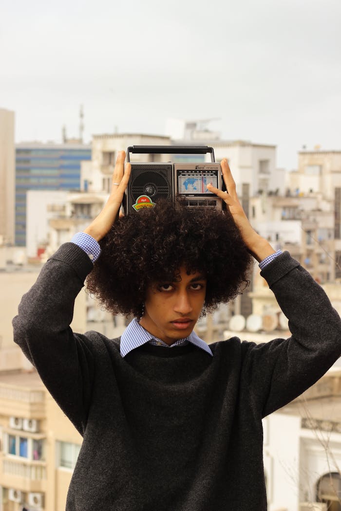 A young adult in Casablanca holds a vintage radio above their head, contrasting urban backdrop.